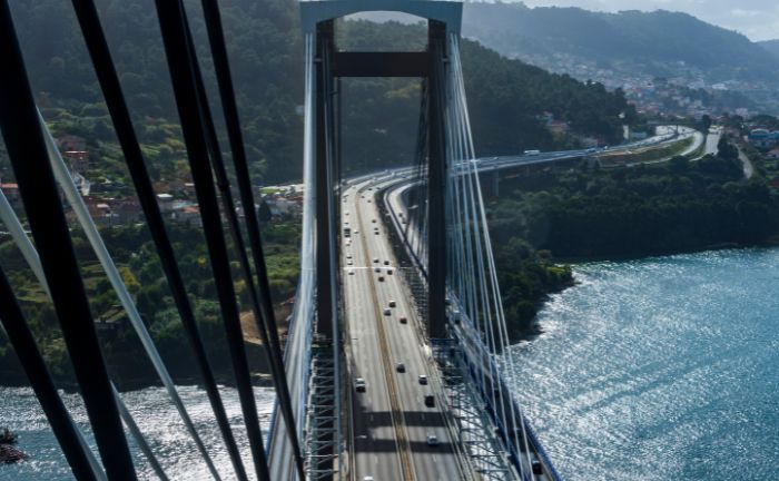 Autobahn auf der Hängebrücke mit Fluss und grüner Landschaft im Hintergrund.