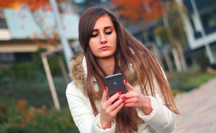 Eine junge Frau schreibt an ihrem Smartphone eine Nachricht