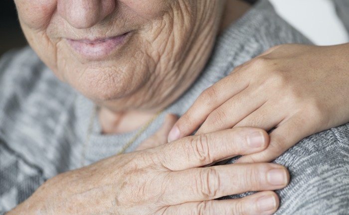 Alte Frau, deren Hand gehalten wird: Schenkungen können von Angehörigen zurückgefordert werden, wenn deren Angehörige die Kosten für das Pflegeheim nicht selbst tragen können.