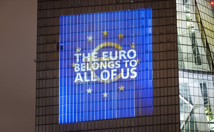 Die Aufschrift „Der Euro gehört uns allen“ leuchtet an der Fassade des EZB-Gebäudes