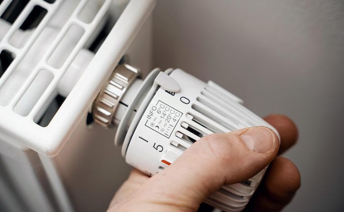 Mann dreht an Heizungsregler