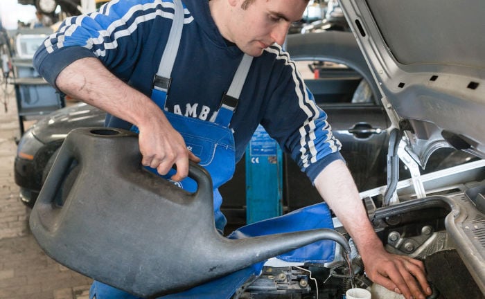 Mechatroniker füllt Kühlwasser im Auto nach