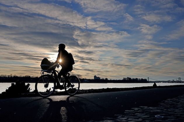 Ein Fahrradfahrer fährt morgens am Rhein entlang