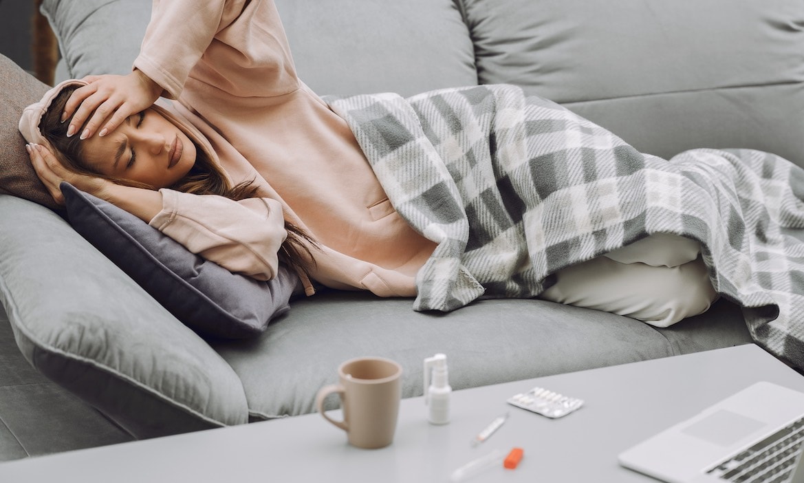 Eine Frau liegt krank auf dem Sofa