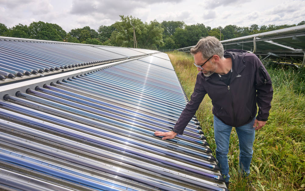 Mitarbeiter der Verbandsgemeindewerke fühlt die Oberflächentemperatur der Vakuumröhren einer Solarthermieanlage im Hunsrück: Hausbesitzer können solche Anlagen auch aufs Dach bauen