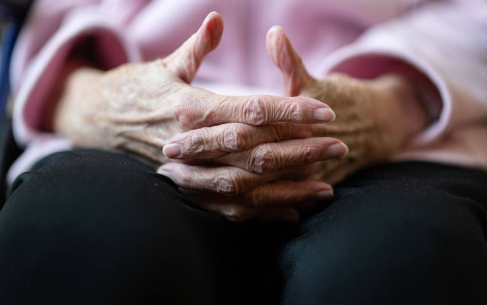 Bewohnerin eines Pflegeheims faltet die Hände: Vierstellige Eigenanteile für Pflegeplätze