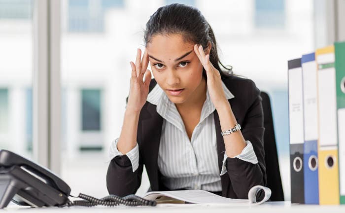 Junge genervte Frau an ihrem Schreibtisch: Bei der CSRD schimpft der GDV über den großen bürokratischen Aufwand.