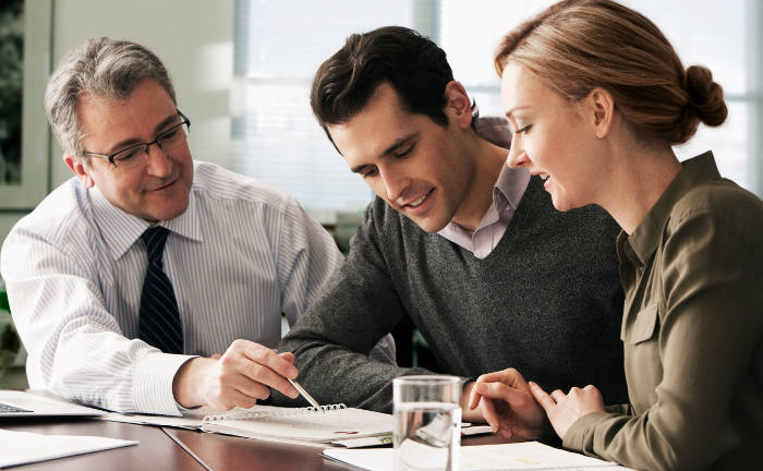 Berater erklärt jungen Mitarbeitern die betriebliche Altersversorgung: Ein guter bau-Versicherer nimmt sich Zeit für die Beratung von Mitarbeitern.