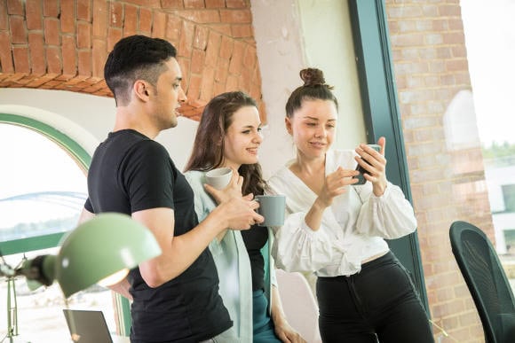 Drei junge Personen schauen gemeinsam auf ein Smartphone (Foto: picture alliance / dpa-tmn | Christin Klose)