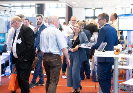 Besucherinnen und Besucher unterhalten sich zu Fachthemen an den Messeständen. Foto: Fonds Finanz