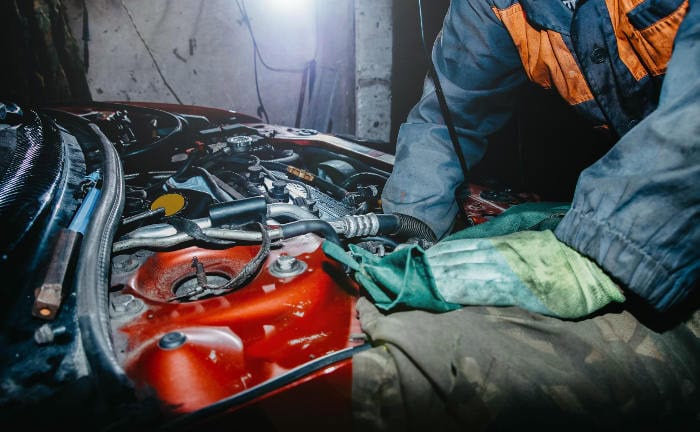 Automechaniker repariert ein kaputtes Auto: Weil die Kosten für Reparaturen steigen, erhöhen Versicherer die Beiträge für KFZ-Versicherungen.