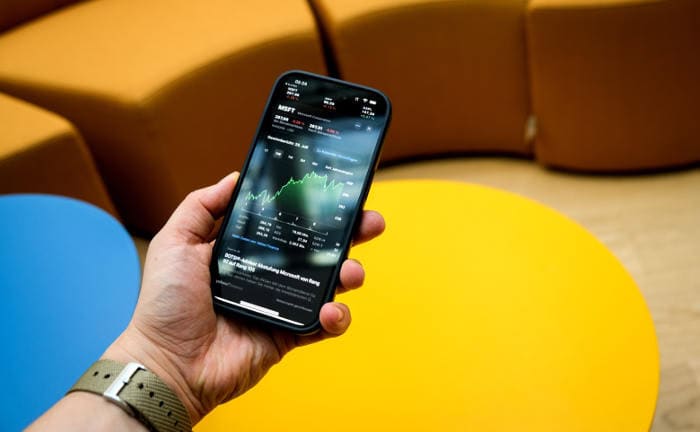 Ein Mann checkt Aktienkurse auf seinem Smartphone: In sozialen Netzwerken sollten Nutzer Geldanlage-Tipps genau überprüfen.
