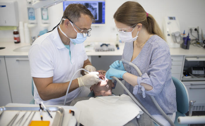 Ein Zahnarzt und eine Mitarbeiterin behandeln die Zähne eines Patienten: Die Aufwendungen der gesetzlichen Krankenkassen für zahnärztliche Behandlungen ohne Zahnersatz stiegen im ersten Halbjahr 2024 laut aktuellen Schätzungen um 3,7 Prozent beziehungsweise 255 Millionen Euro.