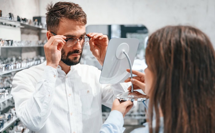 Eine Optikerin hilft einem Kunden bei der Brillen-Auswahl: Eine gern genutzte Leistung in Budgettarifen der bKV ist der Kauf einer neuen Brille.
