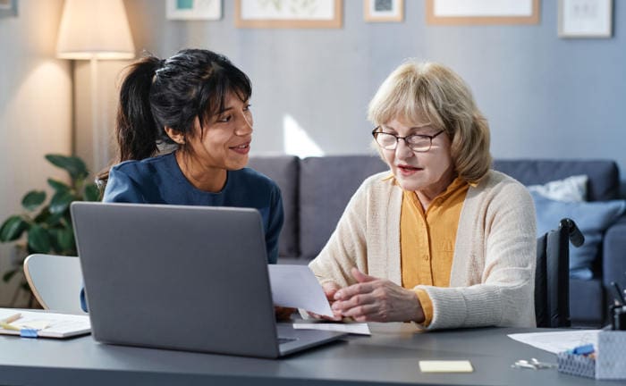 Junge Frau erklärt einer älteren Frau etwas am Laptop: Die bAV ist eine Möglichkeit, um die gesetzliche Rente zu erhöhen.