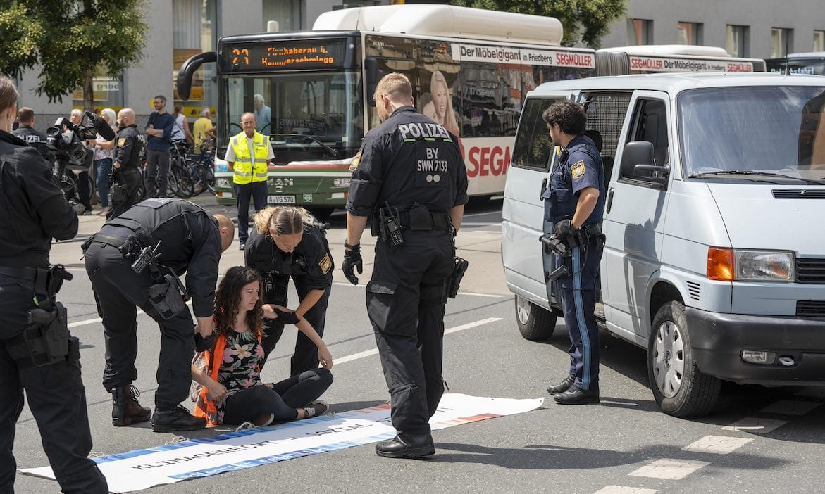 Polizisten versuchen, festgeklebte Klimaaktivisten von der Straße zu bewegen: Der Streit um Klimaschutz sorgt in der deutschen Bevölkerung für gesellschaftliche Spannungen.