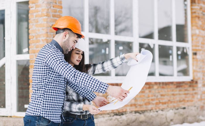 Junges Paar sieht sich gemeinsam Pläne für ihr Haus an: Beim Hauskauf sinken derzeit die Tilgungsraten von Kreditnehmern.