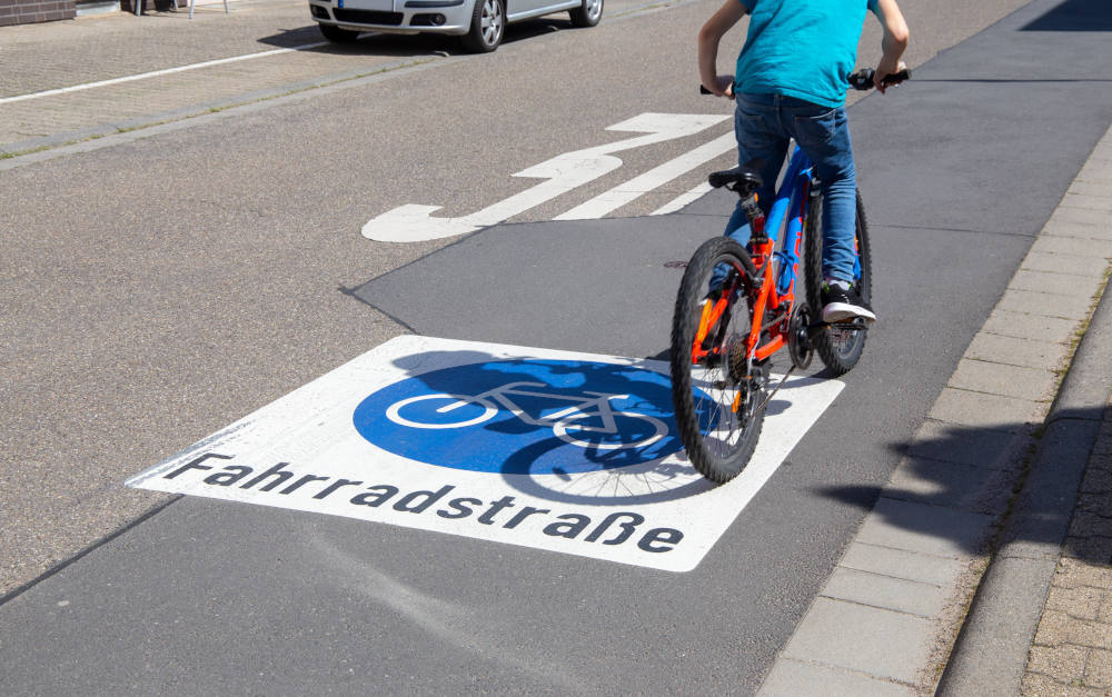 Kind mit Fahrrad im Straßenverkehr (Symbolfoto): Wann greift die Aufsichtspflicht der Eltern?