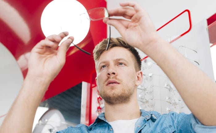 Mann probiert eine Brille beim Optiker an: Eine eigene bKV bieten einige Unternehmen ihren Mitarbeitern an.