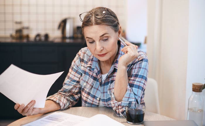 Frau überprüft ihre Finanzen am Küchentisch: Frauen haben ein größeres Risiko für Altersarmut als Männer.