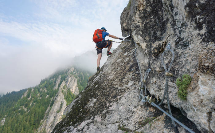 Ein Mann hangelt sich an einem Klettersteig hoch: Risikolebensversicherungen sind wichtig, um nach dem eigenen Tod Hinterbliebene finanziell abzusichern.