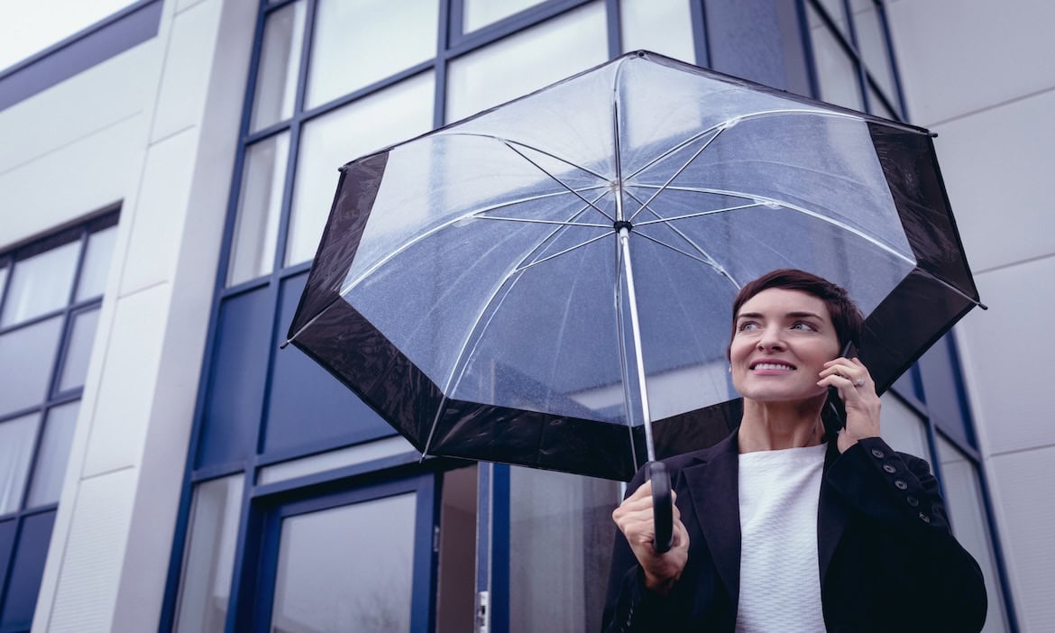 Frau mit Regenschirm: Auch in stürmischen Zeiten bleiben Versicherer stabil.
