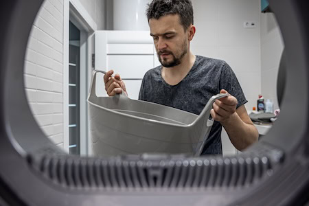 Mann holt Wäsche aus einer kaputten Waschmaschine: Anleger sollten auf genügend Rücklagen für den Notfall achten. Foto: pvproductions / Freepik