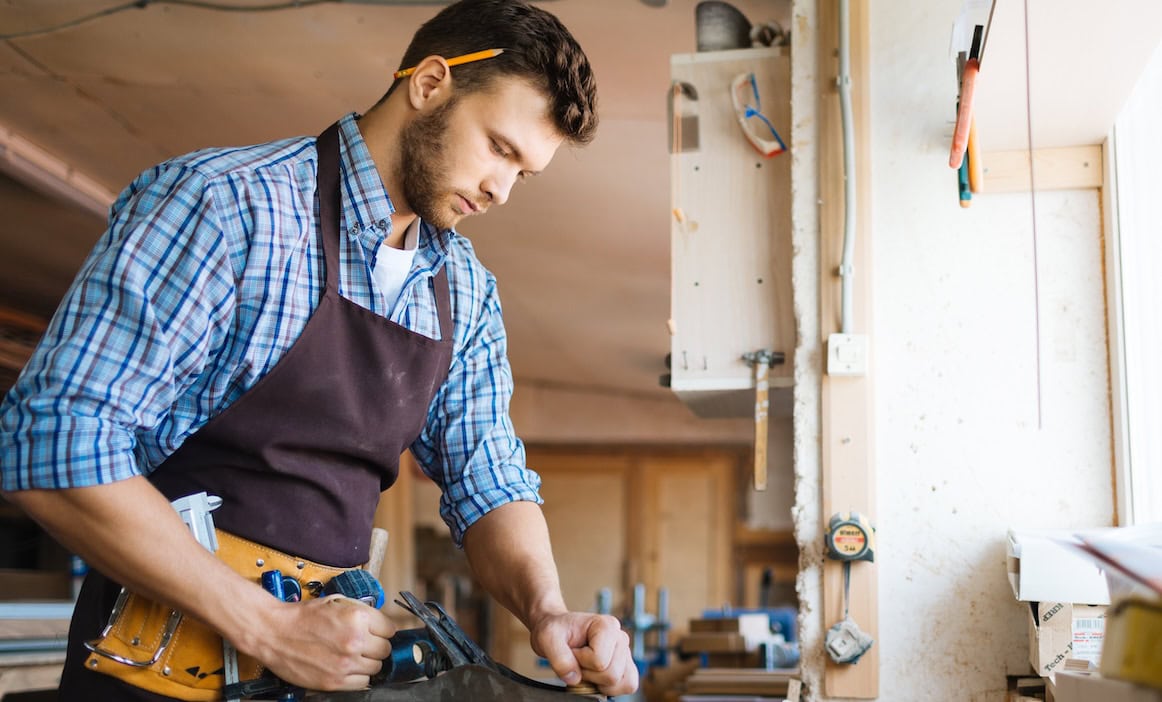 Handwerker arbeitet mit Holz: Eine Betriebshaftpflichtversicherung ist für Unternehmen im Schadensfall sehr wichtig.