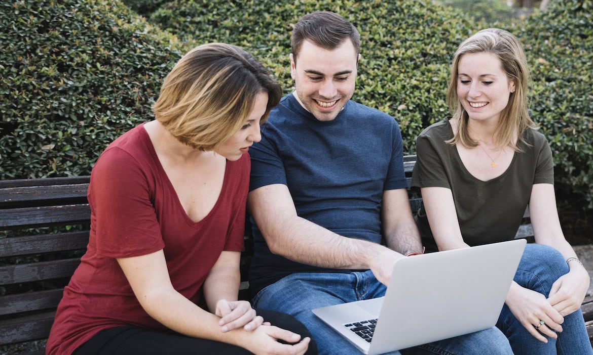 Drei Personen schauen auf einen Laptop: Viele Versicherte trauen dem Online-Abschluss von Versicherungen noch nicht so recht über den Weg.