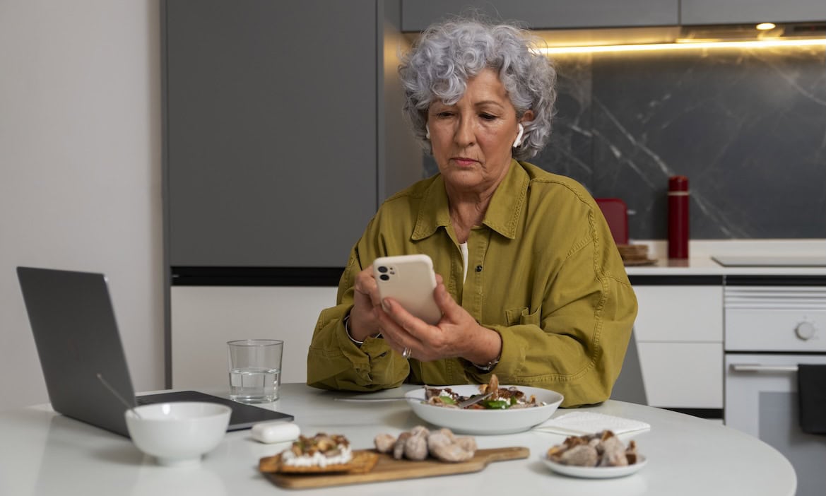 Rentner kontrolliert ihr Smartphone: Auch Rentner, die in Vollzeit gearbeitet haben, haben teils finanzielle Schwierigkeiten im Ruhestand.