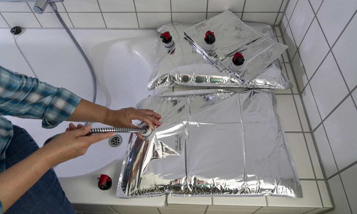 Ein Mann befüllt einen 10-Liter-Wasserbeutel mit Trinkwasser, um bei einem Blackout oder ähnliches gewappnet zu sein.