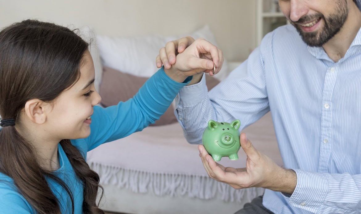 Tochter und Vater befüllen ein Sparschwein: Die Frühstart-Rente könnte einen pädagogischen Effekt haben, vermutet Versicherungsmathematiker Axel Kleinlein.