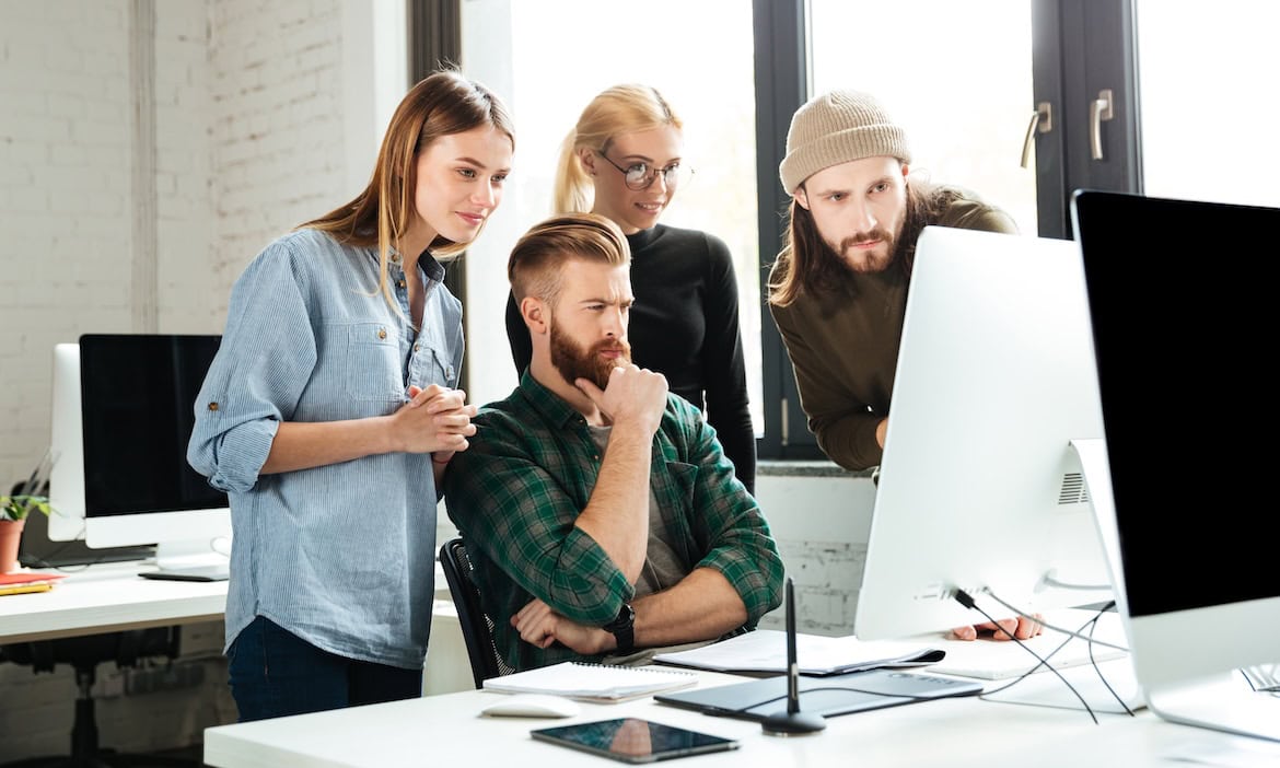 Kollegen vor dem Bildschirm: Nur jeder siebte Unternehmer weiß, wie er künstliche Intelligenz rechtssicher anwendet.