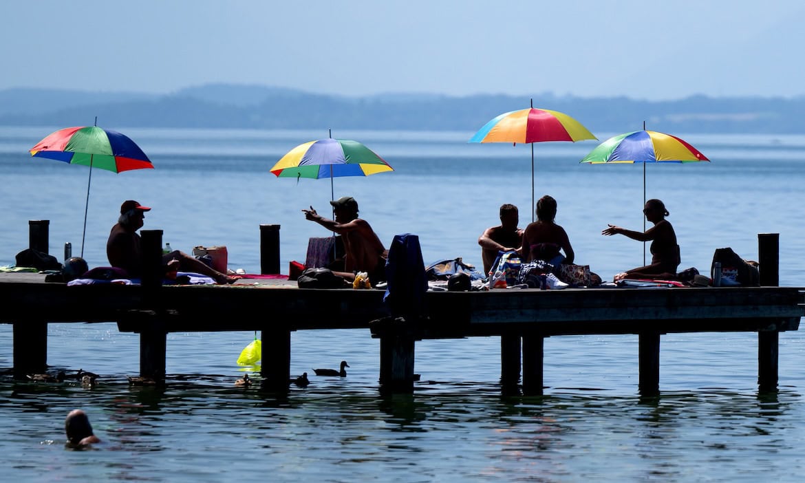Menschen unter Sonnenschirmen am Starnberger See: Im Sommer kann es zu Naturgefahren wie plötzlichem Starkregen kommen.
