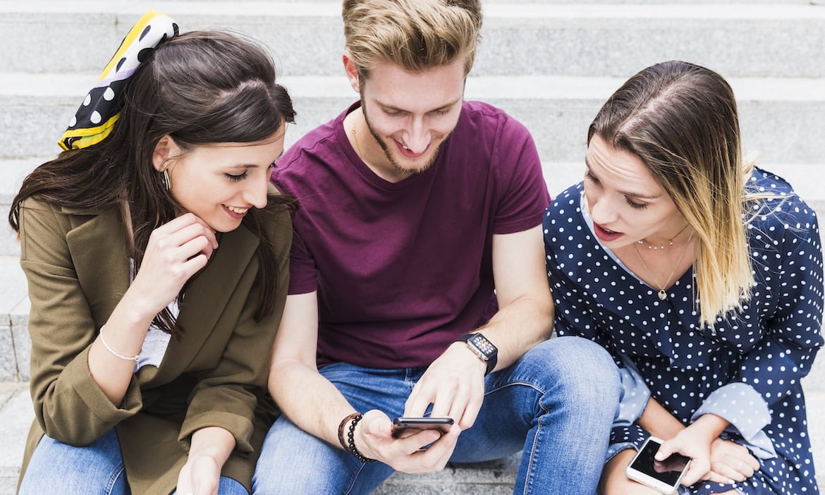 Junge Leute an ihren Smartphones: Mitglieder der GenZ bevorzugen Aktien gegenüber Lebensversicherungen.