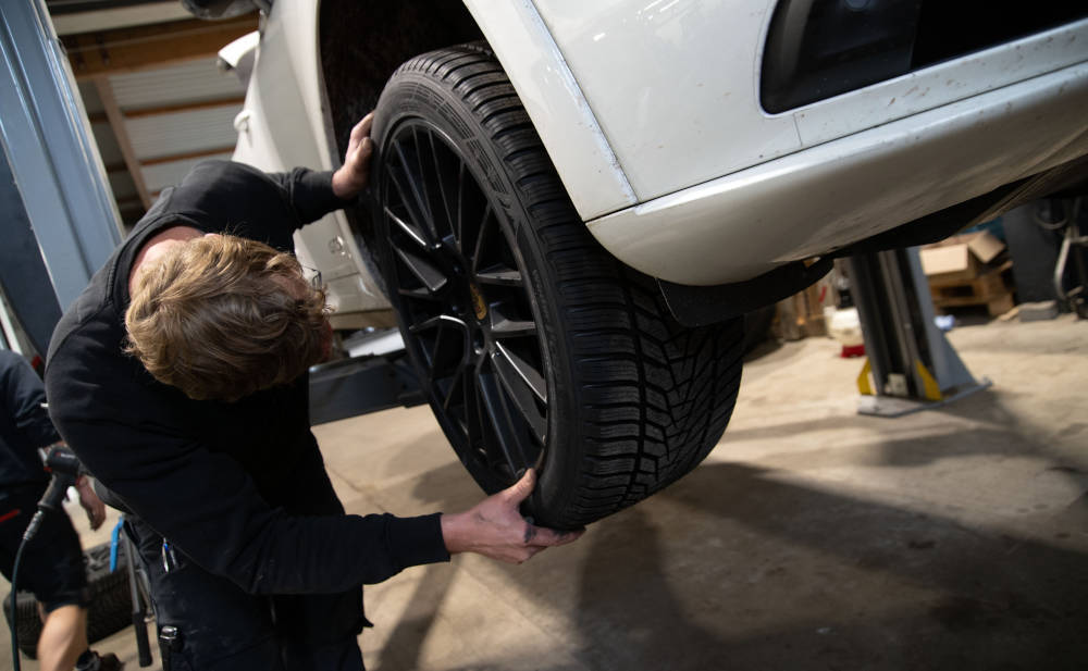 KFZ-Mechaniker schraubt ein Rad ans Auto: Preise für Werkstätten sind wieder gestiegen
