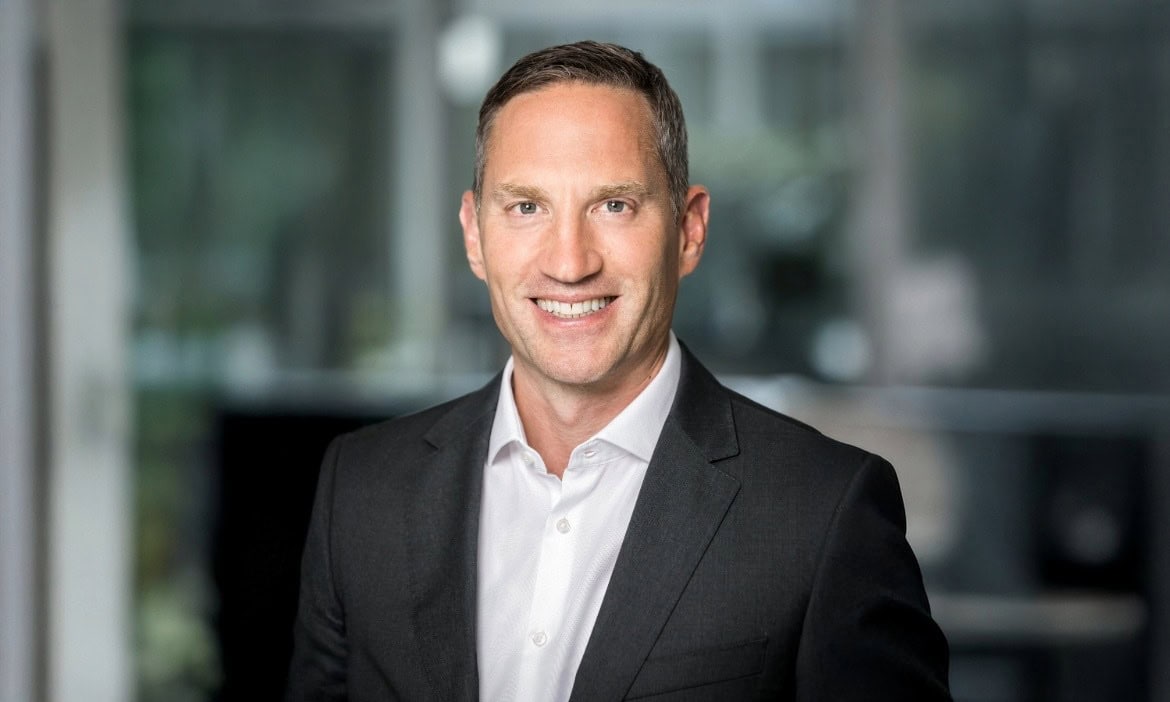 Attraktiver Businessmann in Anzug vor moderner Büroumgebung, professionelles Portrait.