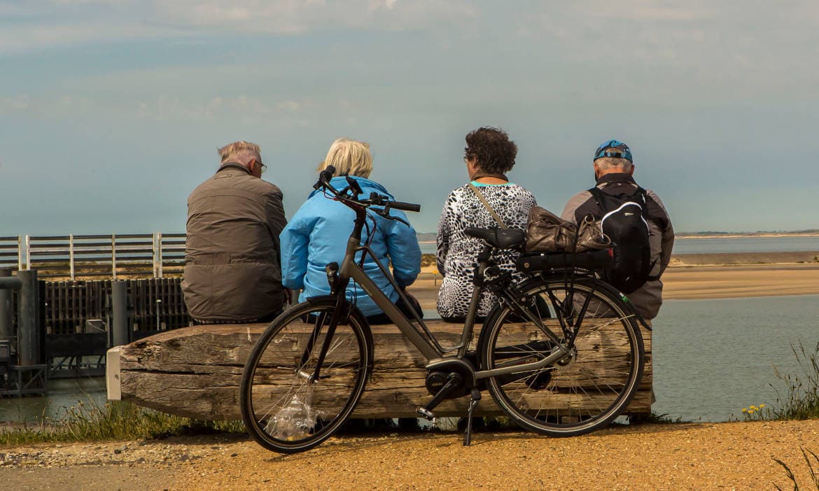 Menschen sitzen am Wasser mit Fahrrad und Rucksack, Outdoor-Aktivitäten in Deutschland.