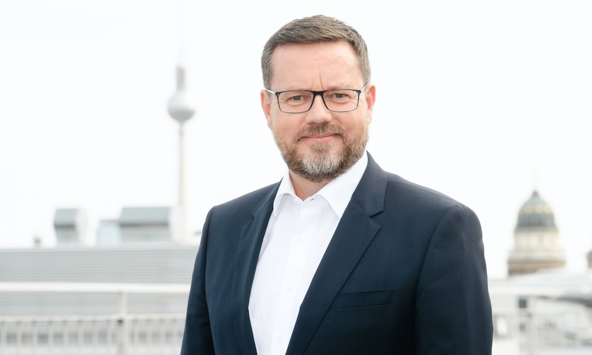 Versicherungsberater in formeller Kleidung vor städtischer Skyline, professionelle Beratung.